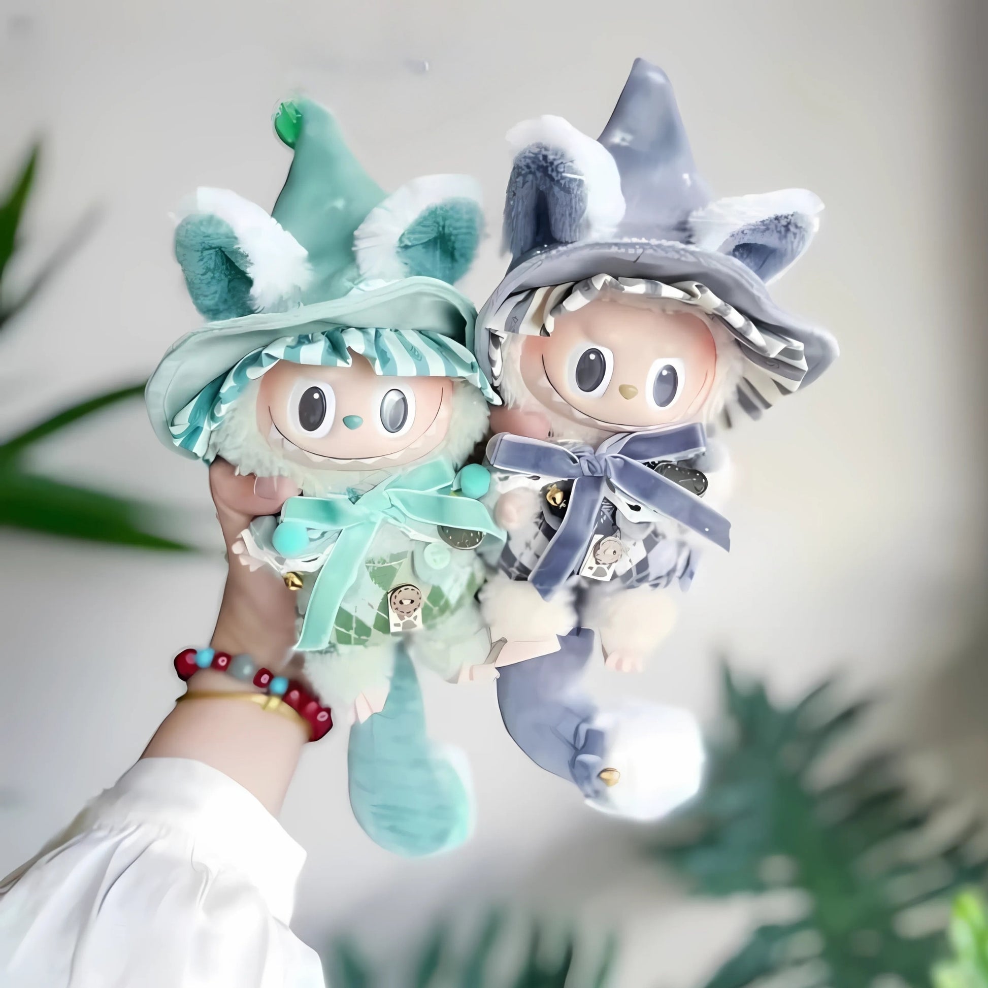Two colorful gnome dolls held by a person with a blurred green plant background