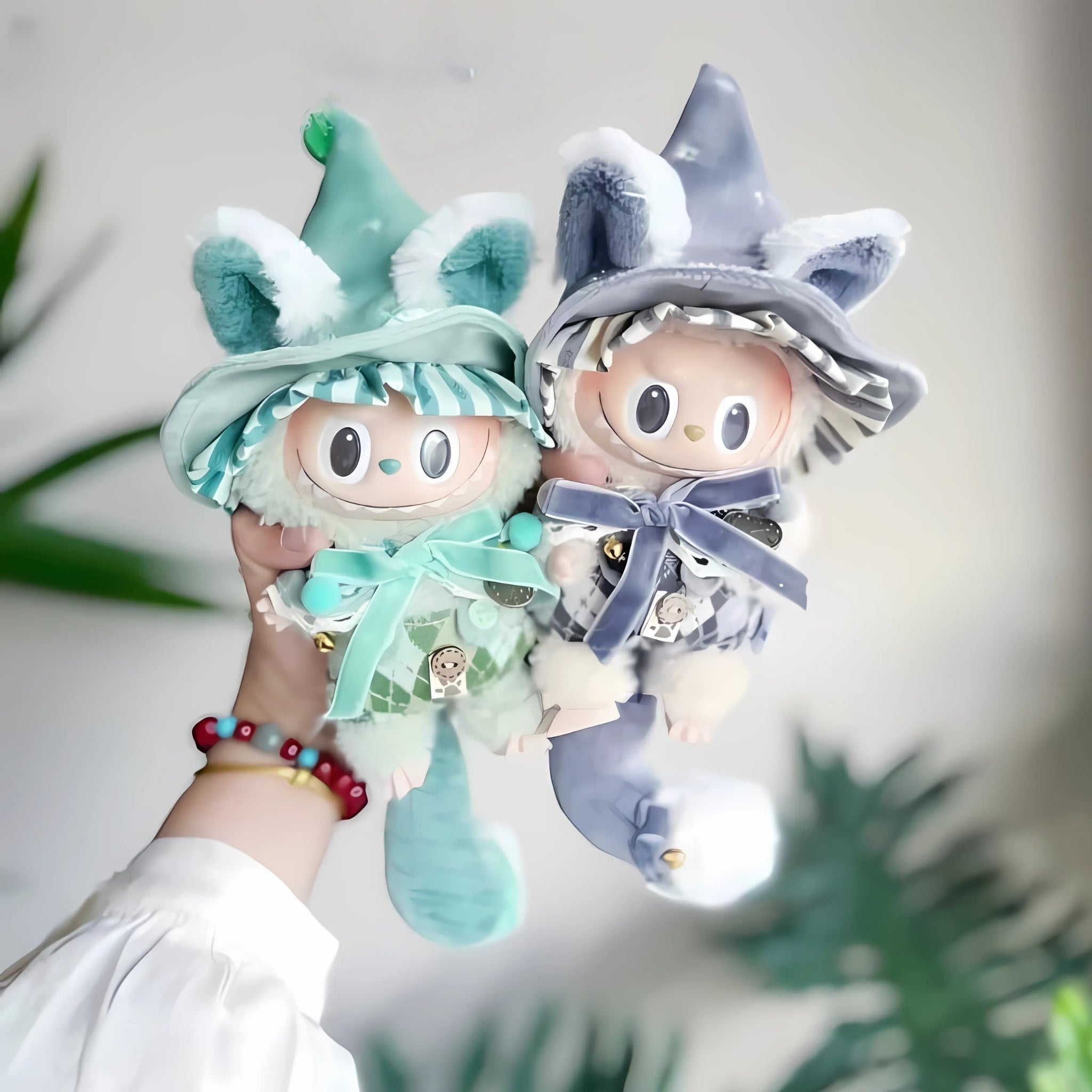 Two colorful gnome dolls held by a person with a blurred green plant background