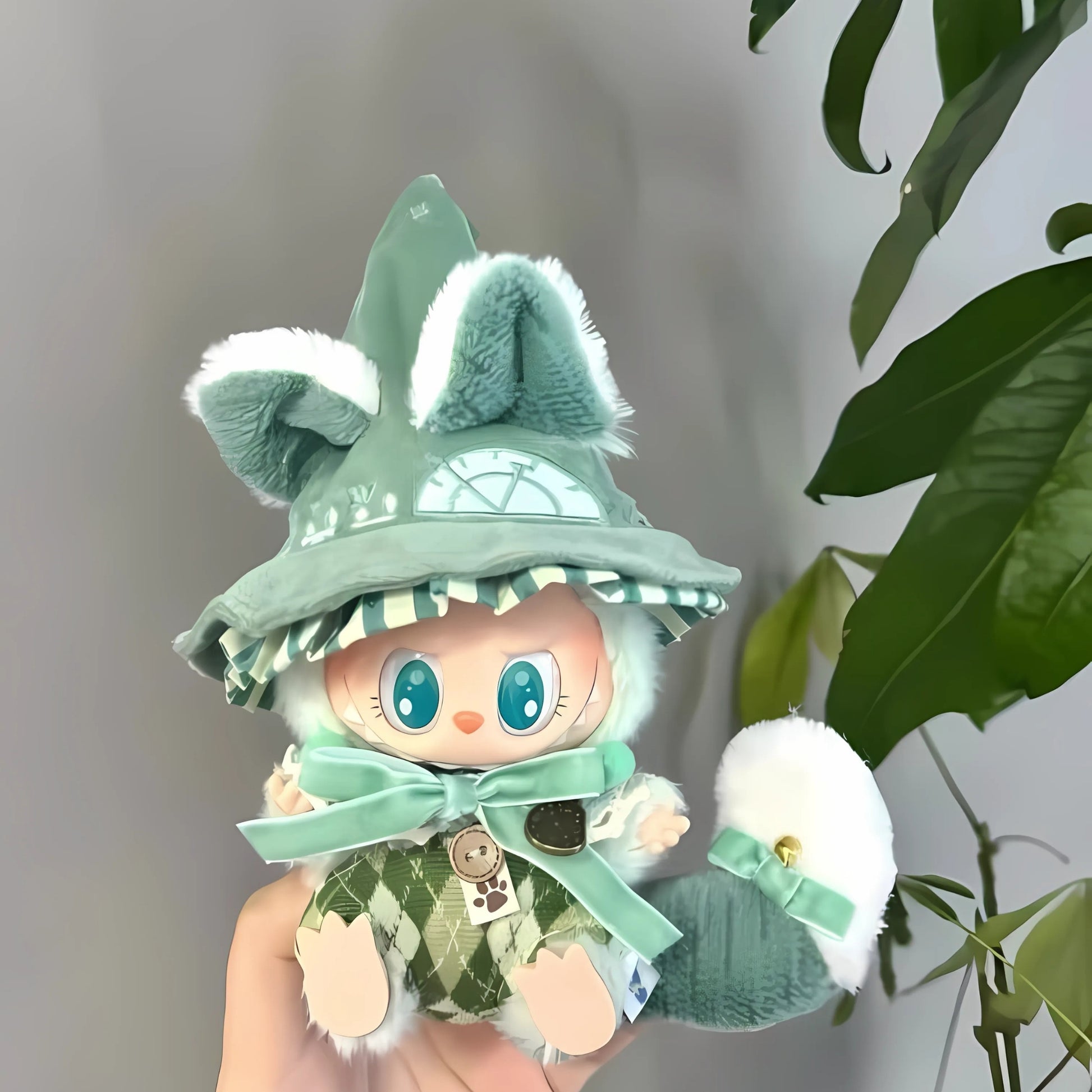 Toy figure with green outfit and hat held by a hand, plant in the background
