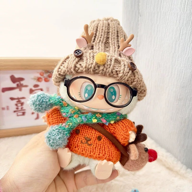 Toy figure of a character wearing a knitted hat with antlers, glasses, and an orange sweater.