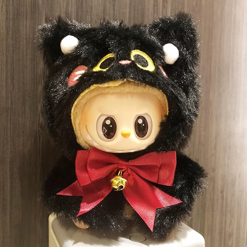 Plush toy with black fur, red bow, and yellow eyes on a wooden background
