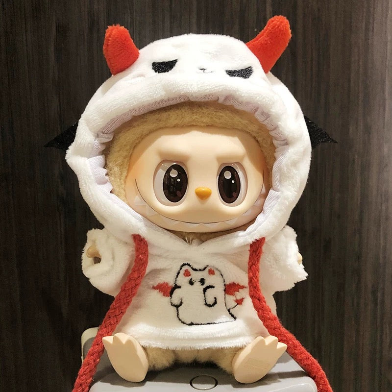 Toy figure wearing a white hood with red accents and a small design on a dark background