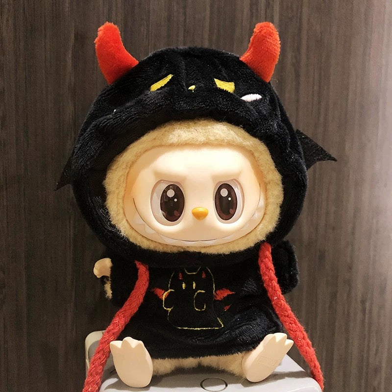 Plush toy with a black hood and red horns on a wooden background