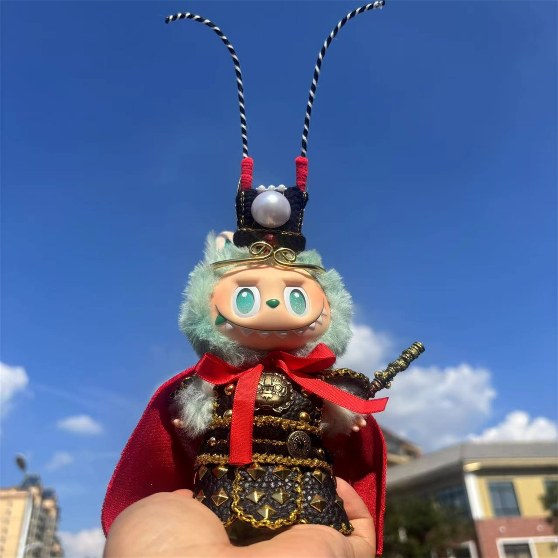 Toy figure with a red cape and black headgear against a blue sky